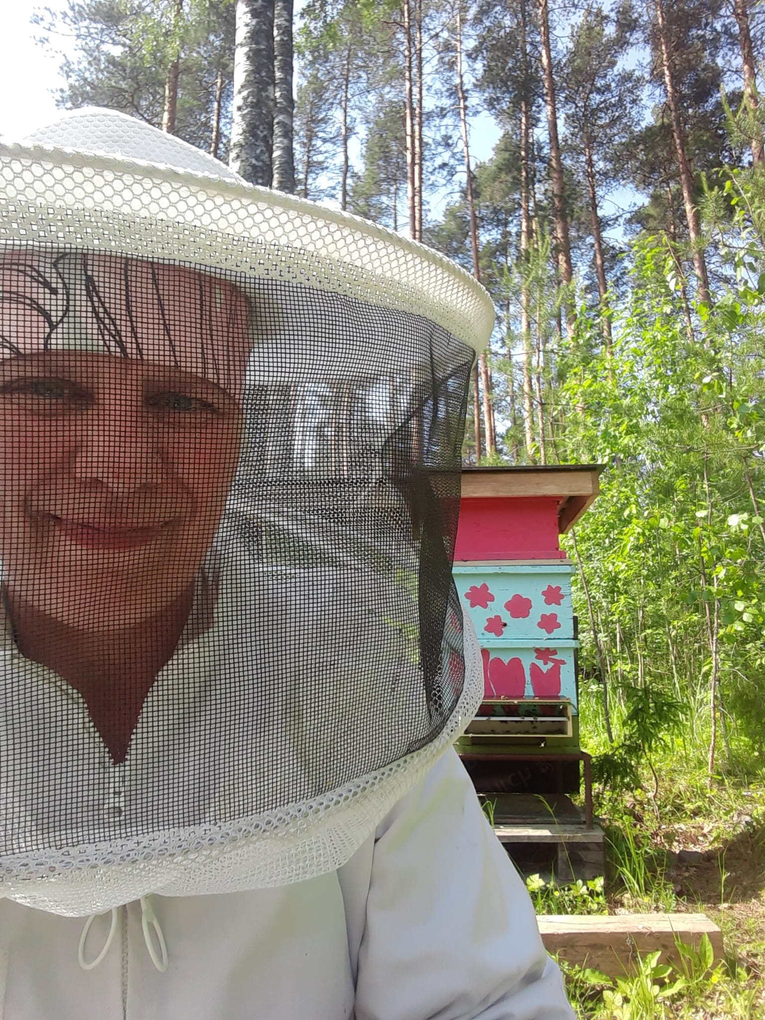 Nainen mehiläistarhurin suojavaatteissa.