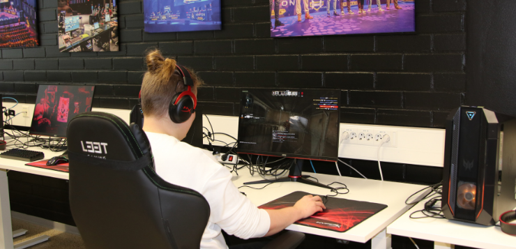 Opiskelija pelaamassa tietokoneella Valkeakosken kampuksen HAMK Gaming Lab -tilassa.