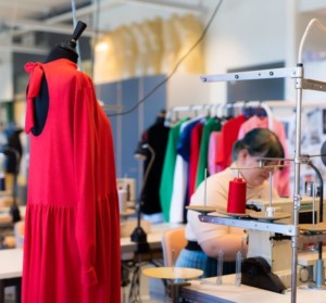 Fashion design student sewing and some outfits on display