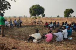 Joukko afrikkalaisia maanviljelijöitä istuu pellon reunalla