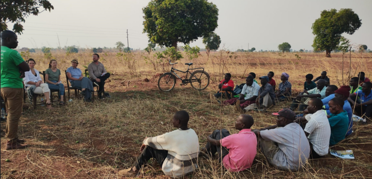 Joukko afrikkalaisia maanviljelijöitä istuu pellon reunalla