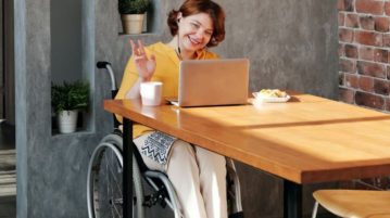 nainen pyörätuolissa tietokoneen äärellä