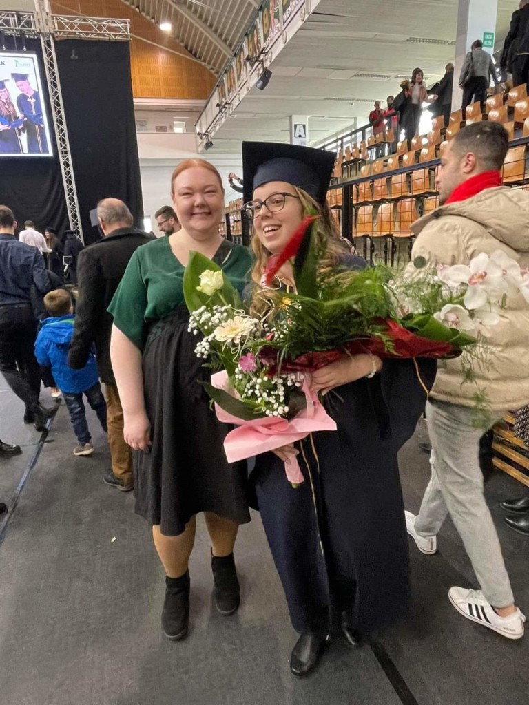 Two women. One of them wearing graduation ceremony oufit